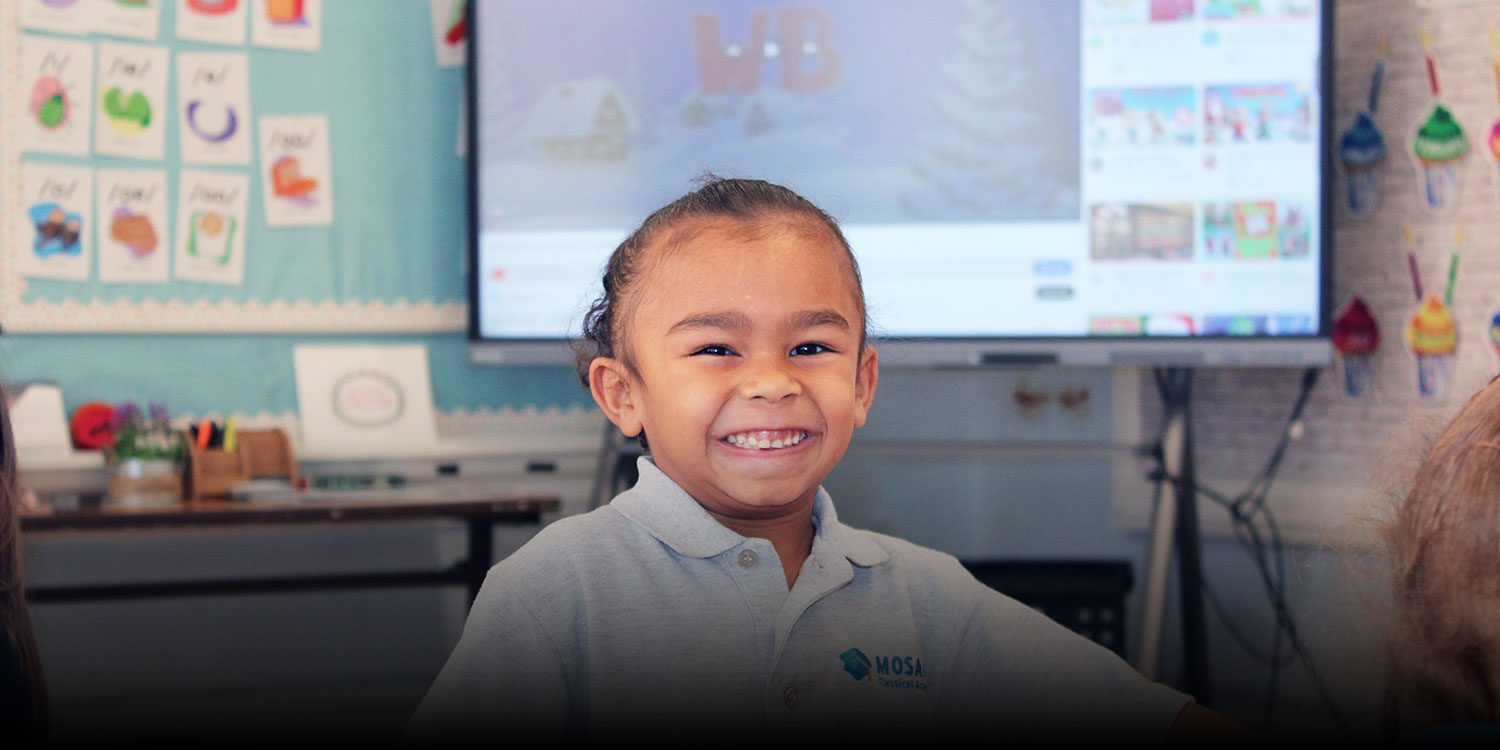 Young student smiling in a classroom.